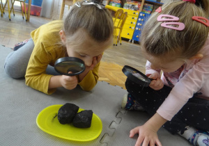 Dzieci obserwują węgiel przy pomocy lupy